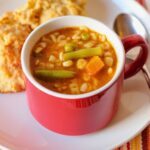 overhead shot of alphabet soup with biscuits on plate.