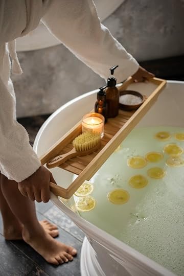 Person in bathrobe placing spa items over a luxury lemon bath as part of a monthly self-care ritual to embody financial abundance.