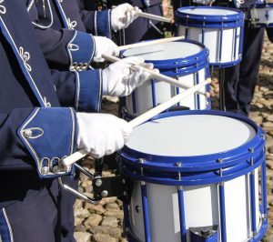 drummers hands showing blue sleeves and white gloves playing drums