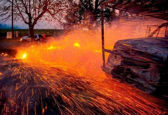 TOPSHOT - Fire and embers blow around a burnt utility truck during the Kincade fire in Healdsburg, California on October 27, 2019. - Powerful winds were fanning wildfires in northern California in 