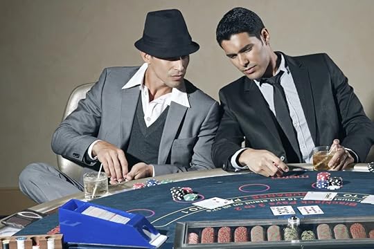 Two well-dressed men, one wearing a fedora, intently playing cards at a blackjack table filled with chips and drinks, illustrating the social and strategic aspects of gambling in a casino setting.