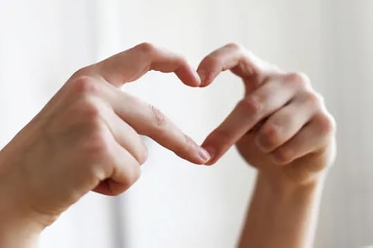 Two hands form a heart shape with their fingers, symbolizing love, care, and compassion in a relationship, set against a soft, light background.
