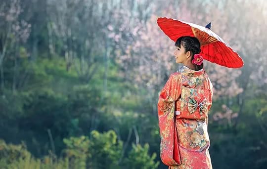 A woman in a red kimono holds a traditional parasol under a cherry blossom tree, looking over a natural landscape.
