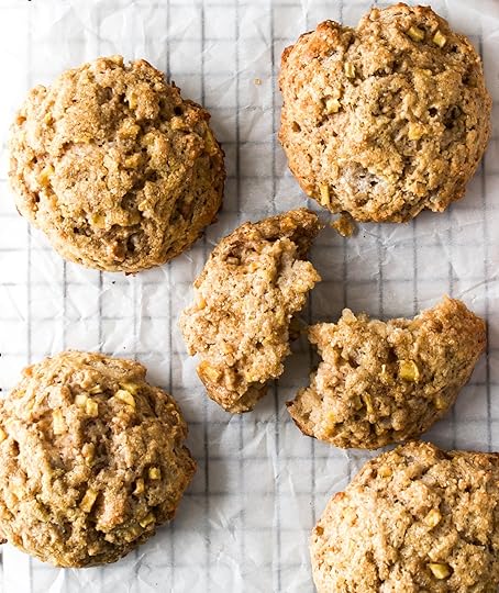 A collection of homemade apple cinnamon scones on a baking rack, with one broken open to show the fluffy interior and another drizzled with a simple white glaze.