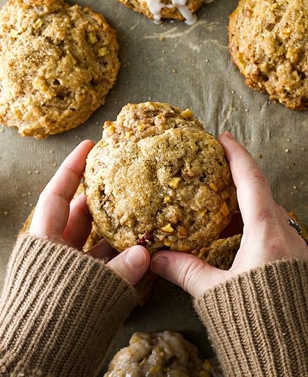 Hands in a cozy brown sweater holding up a freshly baked homemade apple cinnamon scone.