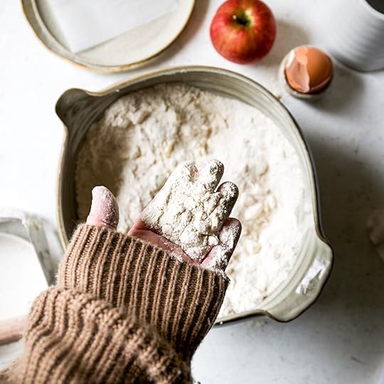 A hand holding up a handful of the flour and butter mixture to show the proper crumbly texture for scone dough.