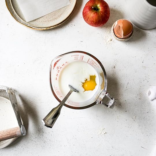 A liquid measuring cup with an egg and buttermilk being mixed together with a fork, a step for the apple scone recipe.