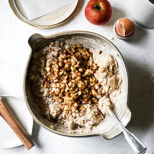 Finely diced apples and spices being added to the shaggy scone dough in a mixing bowl.