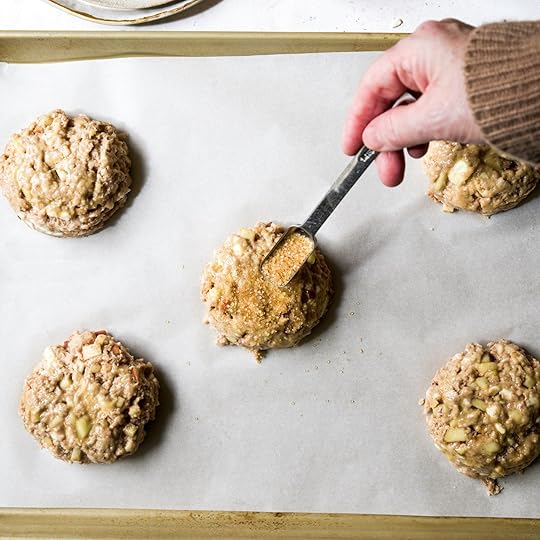 A hand sprinkling Demerara sugar onto unbaked scone dough on a baking sheet