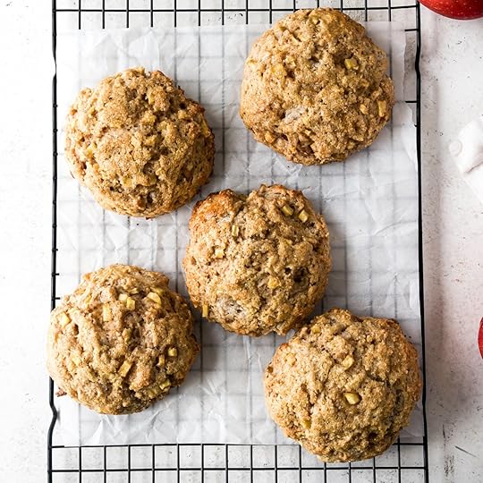 Five freshly baked, rustic homemade apple cinnamon scones arranged on a cooling rack over parchment paper.
