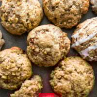 A close-up shot of several homemade apple cinnamon scones on a baking sheet, with a few of the scones drizzled with a simple white glaze.