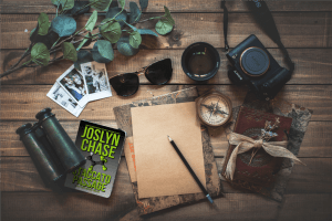 Desk scattered with spy gear, including a copy of Staccato Passage, by Joslyn Chase