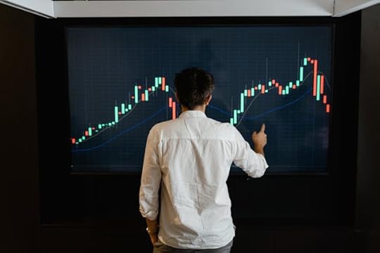 Man studying a stock market chart on a large screen, representing financial growth and millionaire mindset secrets to raise income.