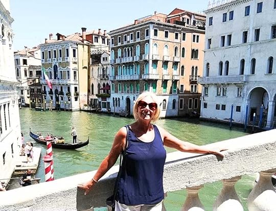 Janice Horton standing on a bridge over a canal and enjoying Venice