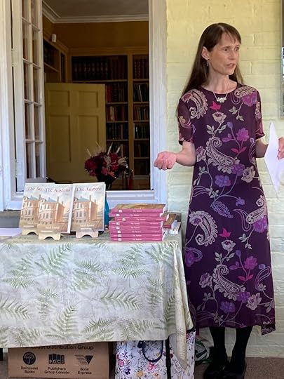 Sarah Emsley, wearing a purple dress, addresses the audience