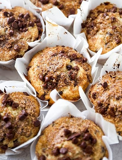 Bakery-style chocolate chip muffins with tall crowns, mini chocolate chips, and a cinnamon brown sugar streusel topping in white paper liners. Overhead shot.