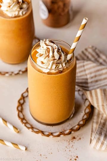 pumpkin pie smoothie in glass cup with whipped cream and striped straw.