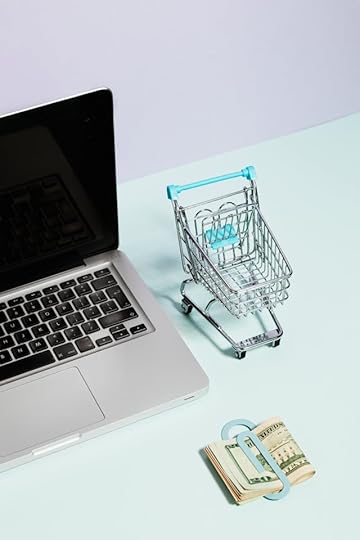Laptop with a miniature shopping cart and stack of U.S. dollars, illustrating how to stop being broke by creating online income streams
