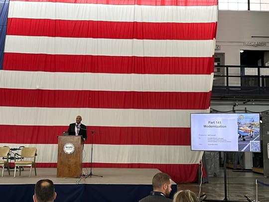 Head of FAA AFS-810 Everette Ruchon presented at the NAFI Summit on the progress on Part 141 Modernization. Everette stands behind a podium in front of a large US flag.