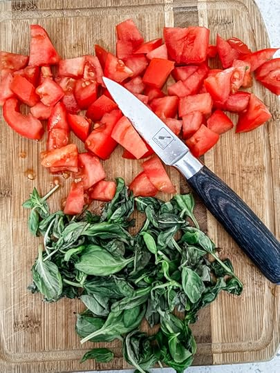 Diced tomatoes and basil on a wooden cutting board