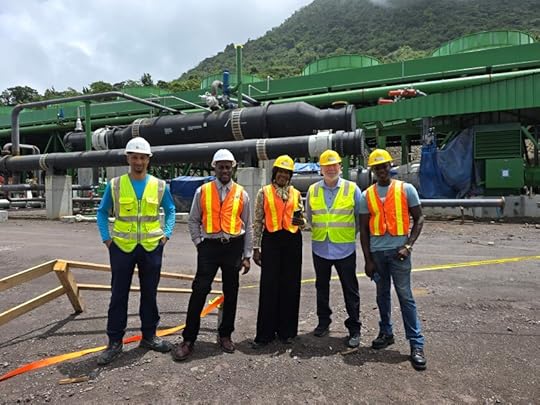 Group of five individuals wearing safety vests and hard hats standing in front of industrial equipment in a mountainous area.