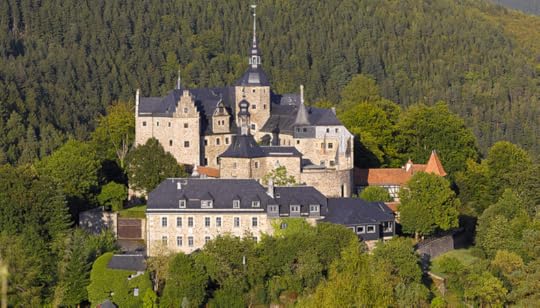 Aerial view of Castle Lauenstein, showcasing its historical architecture surrounded by lush greenery and trees.