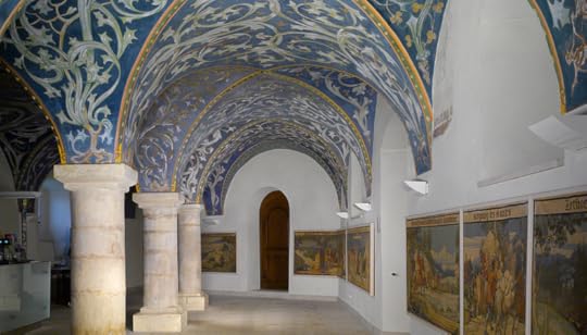 Interior view of Castle Lauenstein (Orlamünde Hall) featuring detailed blue and white frescoes of foliage on the vaulted ceiling, stone columns, and historical artwork displayed on the walls.