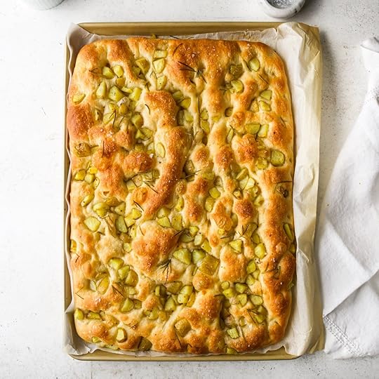 An overhead view of a large, freshly baked tray of golden-brown potato focaccia still in the baking sheet.