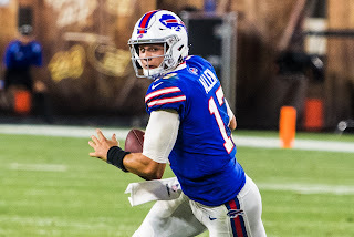 Image of a football player wearing a blue jersey and white helmet, preparing to throw a football