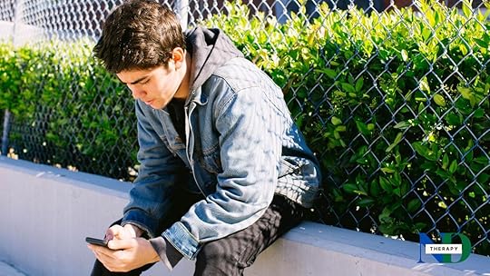 A teen is on his phone outdoors.