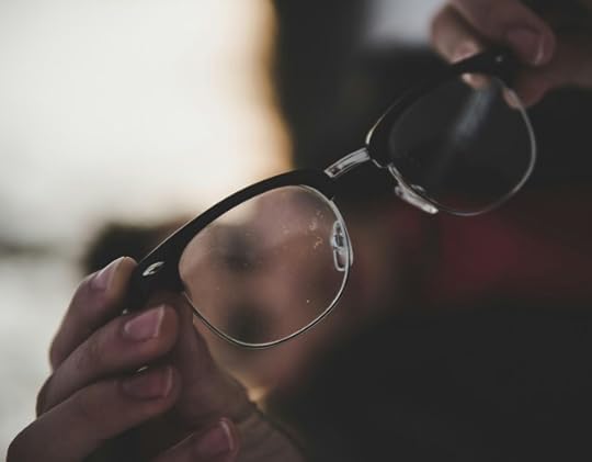 Eyeglasses being held out. Pause and clear the schmutz off your glasses.