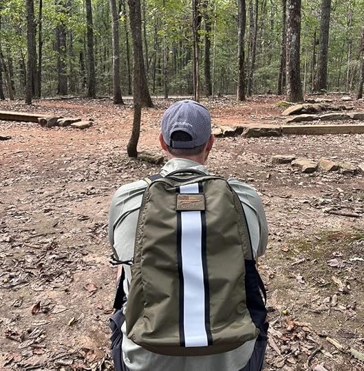 man sitting in woods with goruck basic rucker
