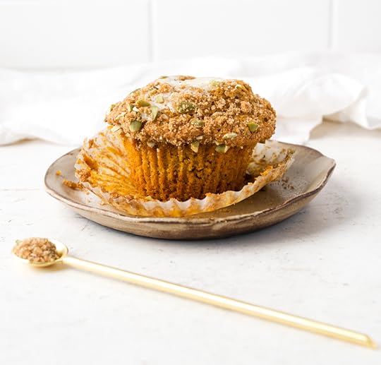 Starbucks Copycat Pumpkin Cream Cheese Muffin on a small plate with a gold spoon holding brown sugar in the foreground. Moist, spiced muffin with streusel, pepitas, and a creamy center.