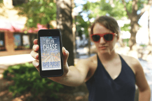 Woman showing her cell phone screen with cover of Rapid Pursuit, by Joslyn Chase