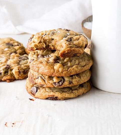 A stack of chocolate chip cookies made with toasted walnuts with the top cookie missing a bite.