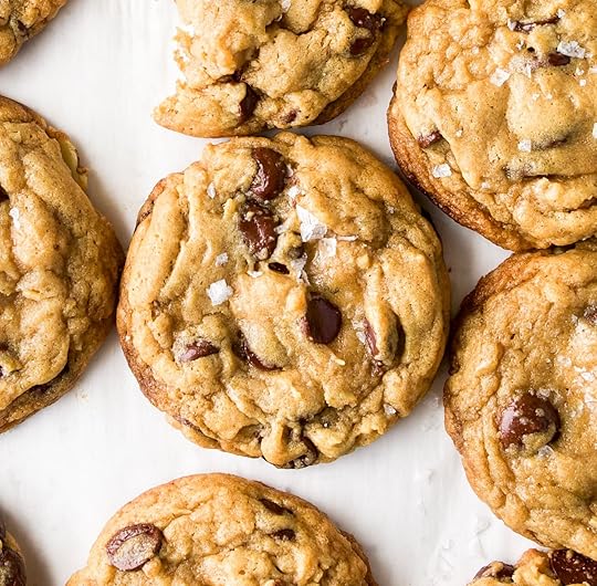 An overhead close up of a chocolate chip cookie made with toasted walnuts and topped with sea salt flakes.
