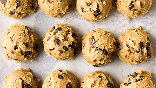 Rows of chocolate chip cookie dough balls on a parchment-lined baking sheet.