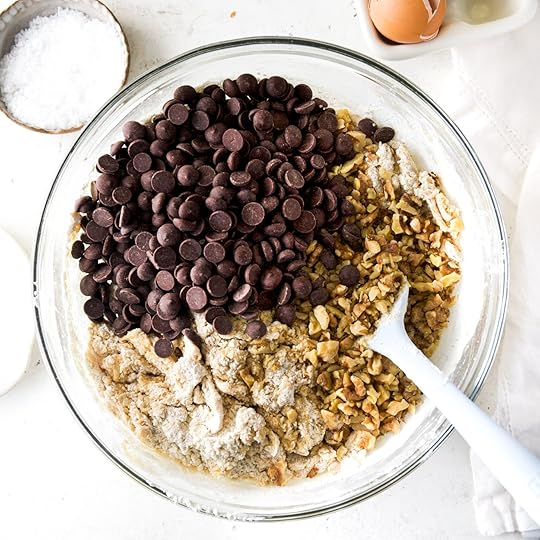 A bowl of cookie dough with chocolate chips and toasted walnuts sitting on top.