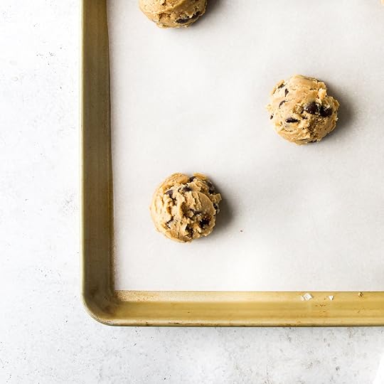 Chocolate chip cookie dough portioned out on a white piece of parchment paper.