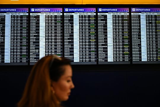 a woman walks by an airport schedule board