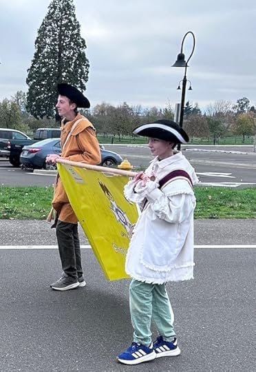 Boys in colonial garb carrying banner in parade.