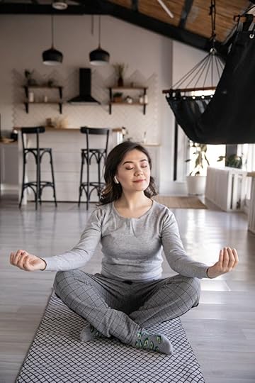 Woman meditating at home on a yoga mat practicing gratitude manifestation