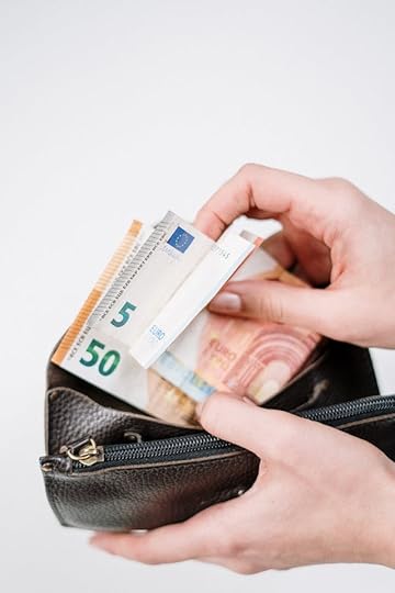 Hand holding a wallet filled with euro notes, showing how can you increase your income by managing everyday money decisions
