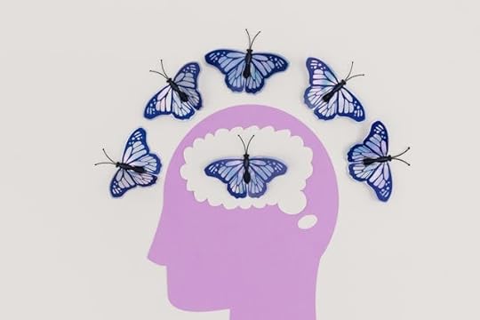 Purple paper silhouette of a head with blue butterflies circling the brain, symbolizing changing reality with your mind.