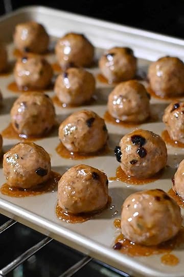 A rimmed sheet pan of reshly baked and glazed cranberry turkey meatballs are ready to be removed from the oven.