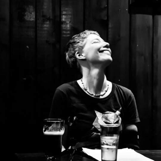 Slightly blurred with movement BW photo of short-haired white woman with her head titled back laughing and a pint of Guinness