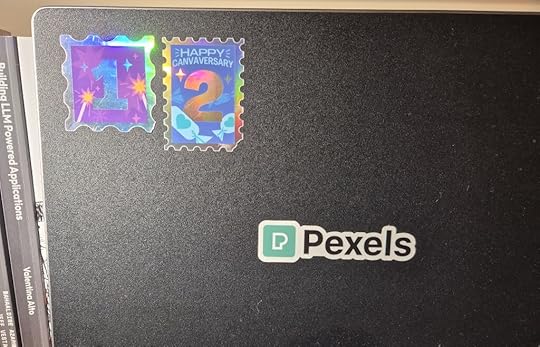 Stickers on a laptop showing '1' and '2' for Canvaversary celebrations, along with a Pexels logo.