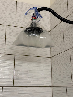 shower head with plastic bag of baking soda and vinegar solution around it