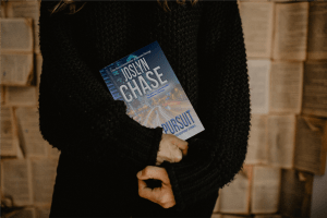 Woman cradling a paperback copy of Rapid Pursuit, by Joslyn Chase