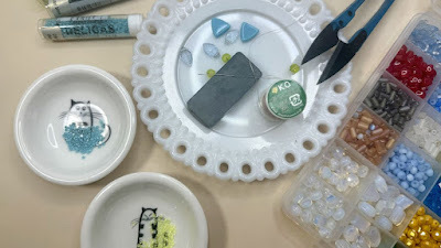 dishes with beads and jewelry making tools and supplies